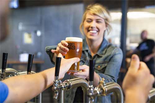 Chica ofreciendo cerveza vegana